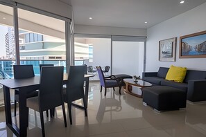 A modern living room with a dining area, a sofa with a yellow pillow, and a coffee table. - Spectacular Ocean View - Infinito Building 1802 (Cartagena)