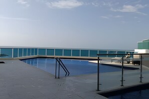 A swimming pool with a glass barrier, a metal ladder, and a view of the ocean. - Spectacular Ocean View - Infinito Building 1802 (Cartagena)