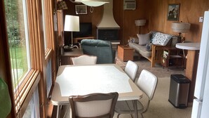 A cozy living room with a dining table, chairs, a sofa, and a television.