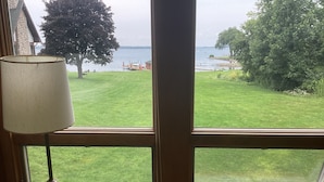 A window with a view of a grassy yard and a body of water.
