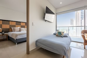 Ein modernes Hotelzimmer mit zwei Betten, einem Flachbildfernseher und einem großen Fenster mit Blick auf die Stadt.