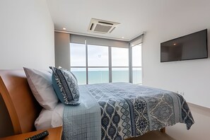 A modern bedroom with a large bed, a TV mounted on the wall, and a view of the sea through large windows. - Apartment Aqua 805 - Morros City (Cartagena)