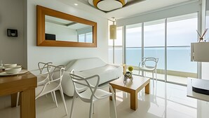 A modern hotel room with a large window, a wooden ceiling, a white sofa, a dining table with chairs, and a mirror on the wall. - Luxurious 3 Bedroom apt - 3303 Palmetto Beach (Cartagena)