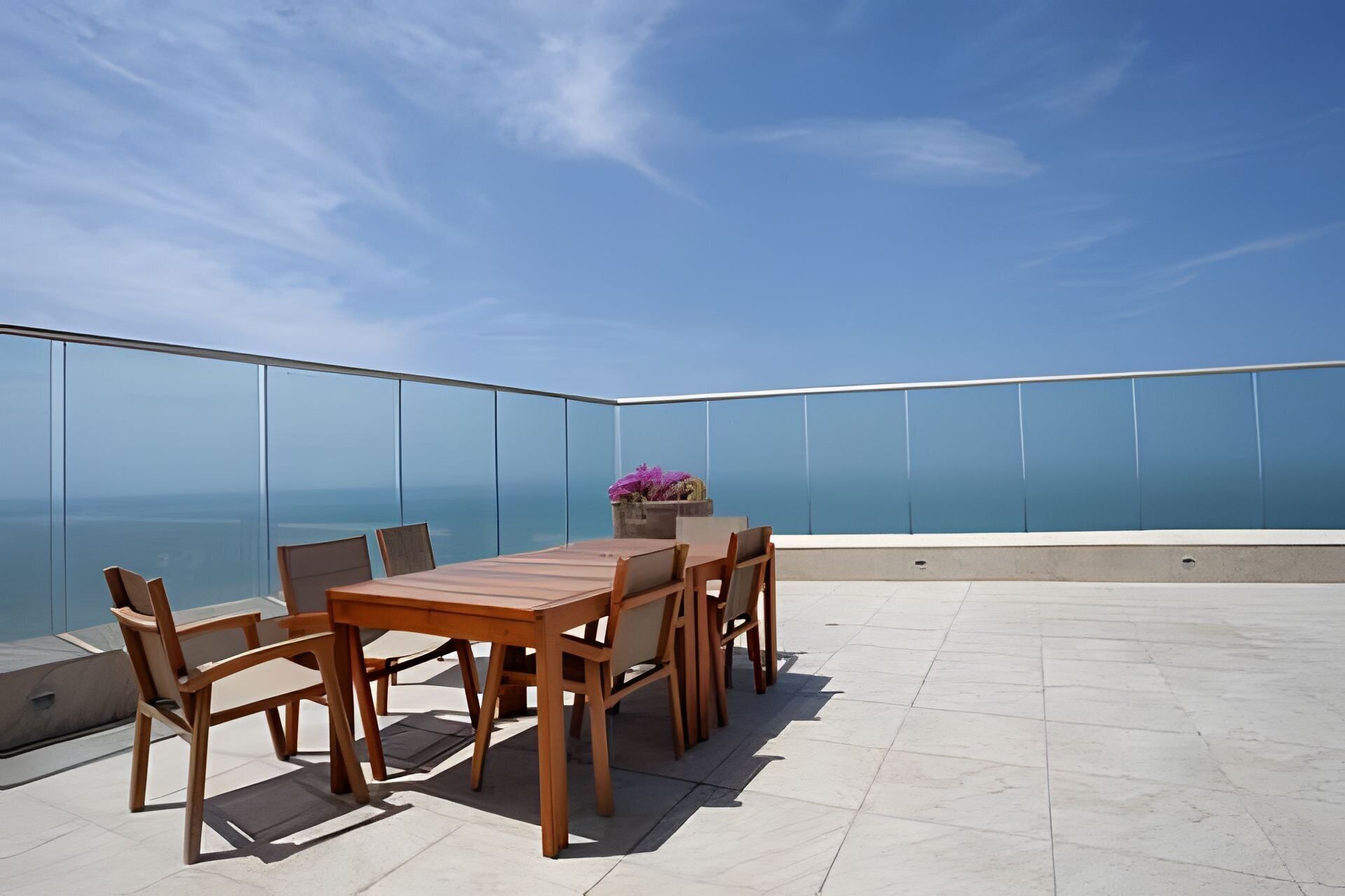 Ein Holztisch und Stühle auf einem Balkon mit freiem Blick auf das Meer.