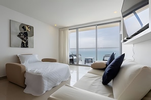 A modern hotel room with a bed, a sofa, a TV mounted on the wall, and a large window offering a view of the sea. - 3605 Morros City - Paradise in Cartagena (Cartagena)