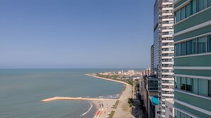 A high-rise hotel overlooking a beach with a clear view of the ocean and a distant cityscape. - Spectacular Ocean View - Ed. Infinito 2302 (Cartagena)