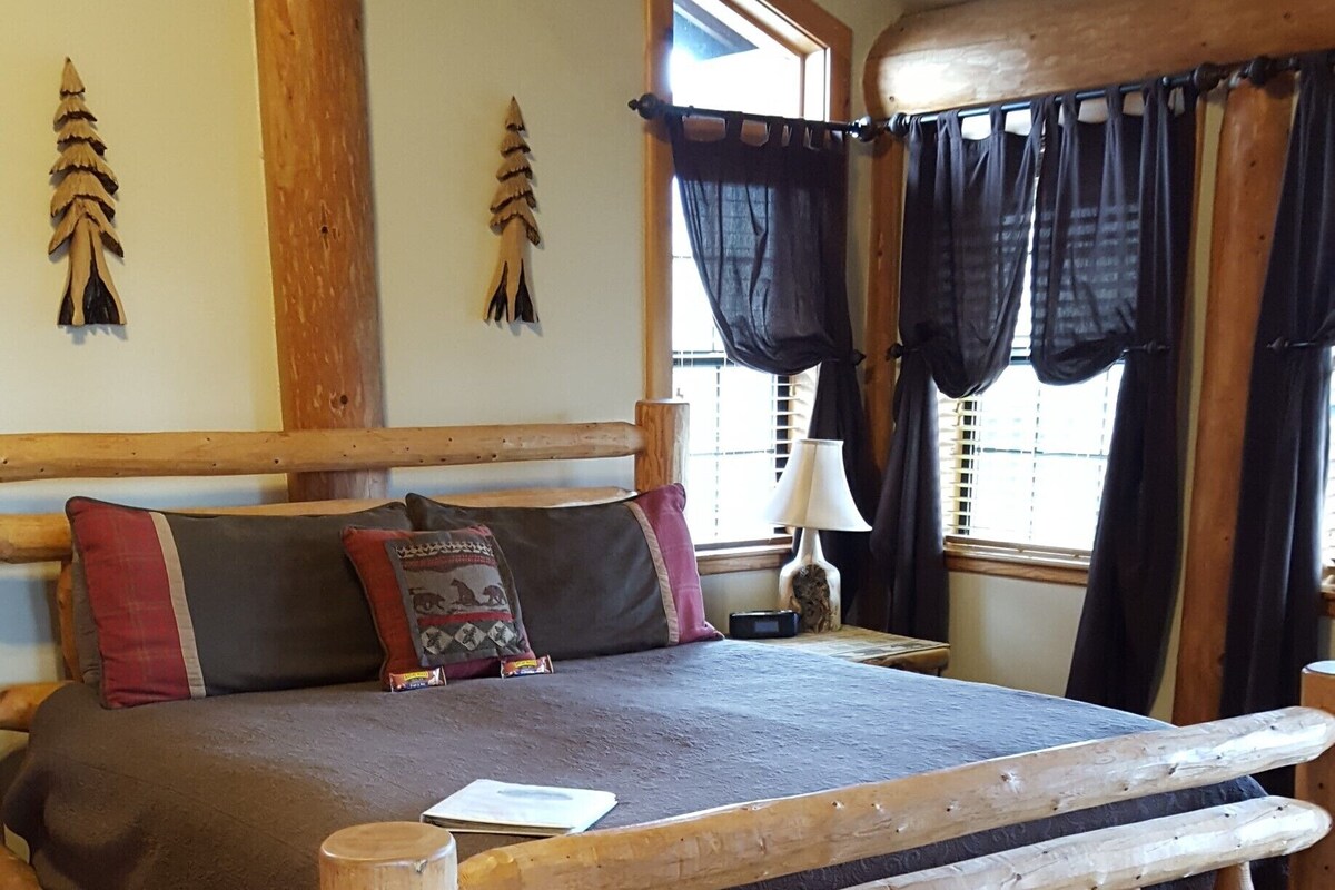A wooden bed with a headboard, a bedside table with a lamp, and a window with curtains.
