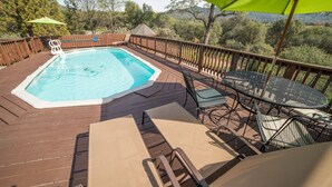 Une terrasse en bois avec un jacuzzi, des chaises longues et une table avec des chaises.