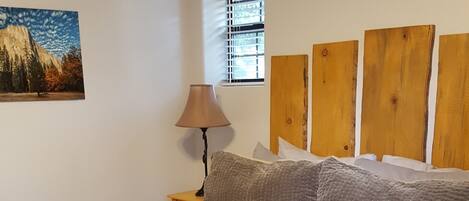 Un lit bien fait, avec une couverture matelassée, un livre posé dessus et une tête de lit en bois.