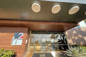 A modern building entrance with a wooden slatted facade, a glass door, and a sign indicating the name 'h2'. - Luxurious 1 bedroom apt - 15th floor of h2 (Cartagena)