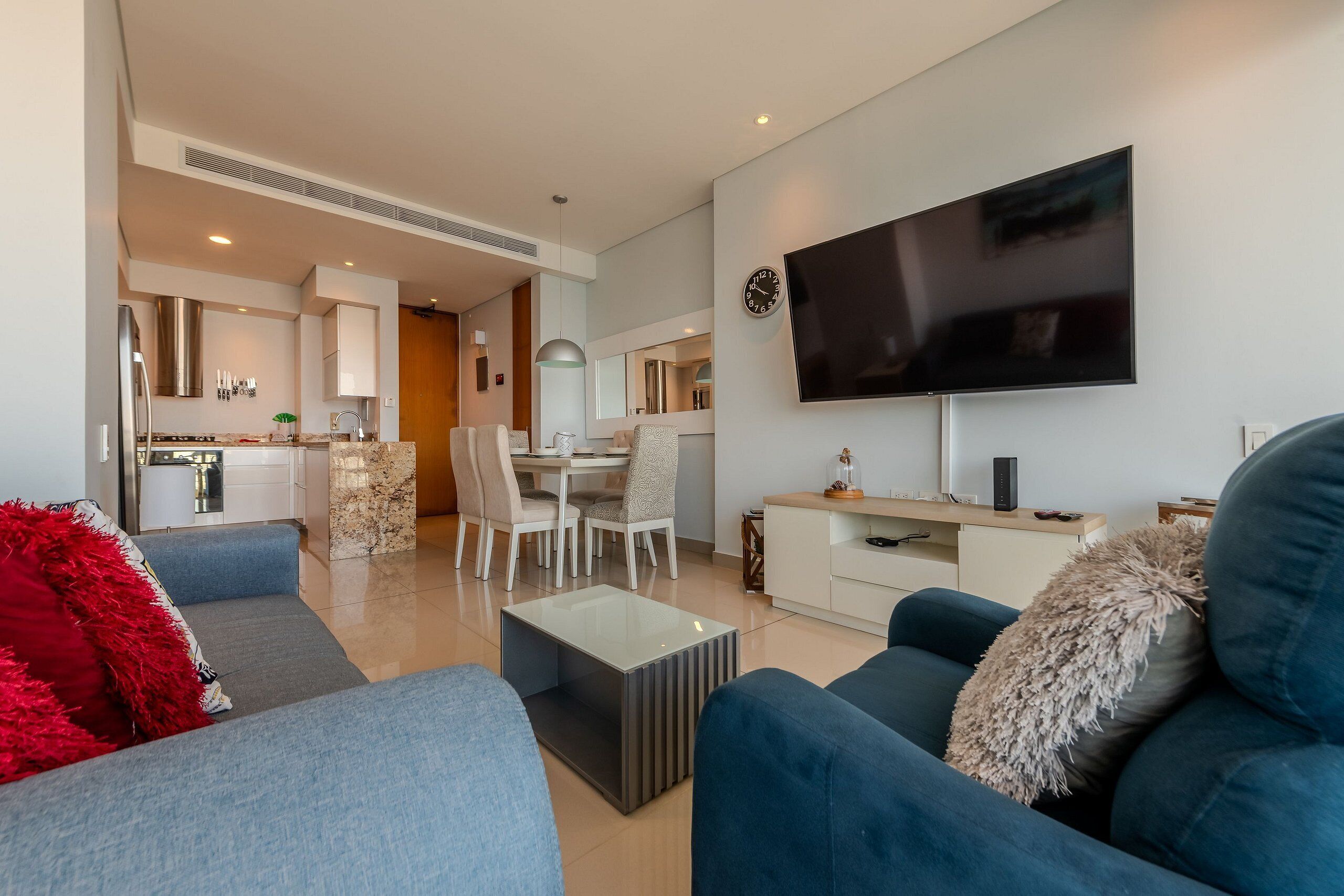 Una sala de estar moderna con televisor, sofá y comedor.