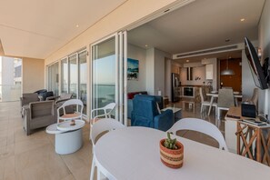 A modern living area with a dining table, chairs, and a sofa. There is a kitchen area with a TV and a dining table. - H2 building -Luxurious 2 BR / 16th Fl - Bocagrande (Cartagena)
