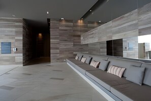 A modern waiting area with a long bench, a large mirror, and a stone-textured wall. - Morros City-Spectacular 38th Floor apt Bocagrande (Cartagena)