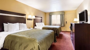 A hotel room with two beds, a TV, a desk, and a wardrobe. - Urban Inn & Suites (Boise)