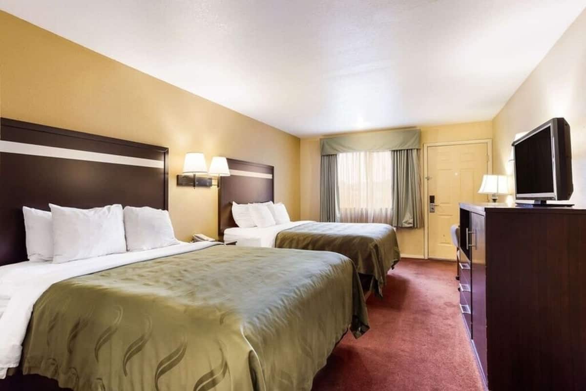A hotel room with two beds, a TV, a desk, and a wardrobe.