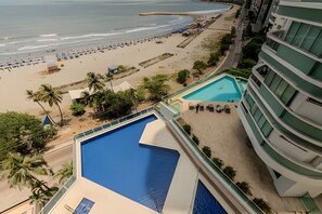 A hotel with a pool, beach view, and palm trees. - Spectacular ocean view - Infinito 1002 Building (Cartagena)