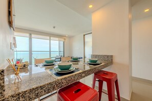 Une cuisine moderne avec des plans de travail en granit, des bols turquoise et des tabourets rouges.