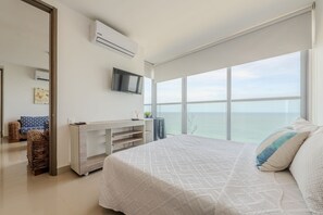 A bedroom with a large bed, a TV mounted on the wall, and a view of the ocean. - 2102 Morros City - Spectacular Ocean View (Cartagena)