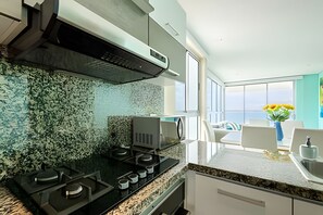 A modern kitchen with a gas stove, granite countertop, and a backsplash with a textured pattern. - 29th Floor Spectacular Apt in Palmetto Beach (Cartagena)
