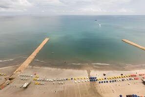 An aerial view of a beach with a wooden jetty extending into the sea, a sandy shore with colorful buoys, and a calm ocean. - 29th Floor Spectacular Apt in Palmetto Beach (Cartagena)