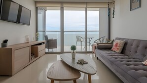 A modern living room with a grey sofa, a wooden coffee table, and a TV mounted on the wall.