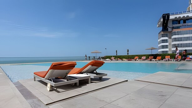 A poolside area with lounge chairs and a view of the ocean.