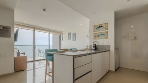 A modern kitchen with a large island, white cabinetry, and artwork on the walls.