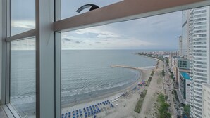 Paesaggio costiero con spiaggia, edifici e vista attraverso una finestra.