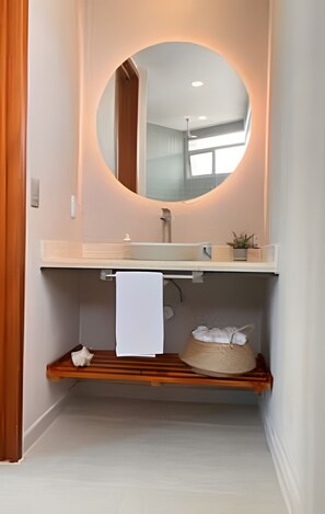 Une salle de bain moderne avec un miroir rond, une étagère en bois et un porte-serviettes.
