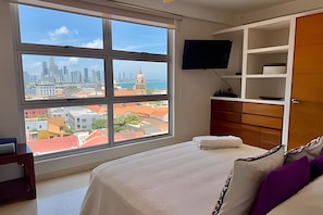 A bedroom with a large window, a bed, a TV, and a wardrobe. - Spectacular 2-bedroom apt in the Historic Center (Cartagena)
