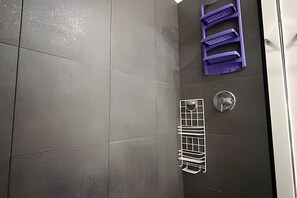 A shower area with a tiled wall, a metal rack, and a purple storage unit. - Beautiful 1 Bedroom Ocean View Apartment - 10th Floor (Cartagena)