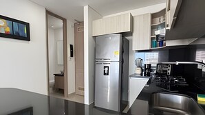 Eine moderne Küche mit einem Edelstahl-Kühlschrank, einem eingebauten Herd und einer Kaffeemaschine.