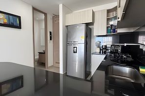 A modern kitchen with a stainless steel refrigerator, a built-in stove, and a coffee maker. - Beautiful 1 Bedroom Ocean View Apartment - 10th Floor (Cartagena)