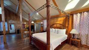 A four-poster bed in a wooden room with a kitchen in the background. - Couples Retreat with King Canopy Bed, Jacuzzi for Two, Fireplace & Pond-View Porch (Zwolle)