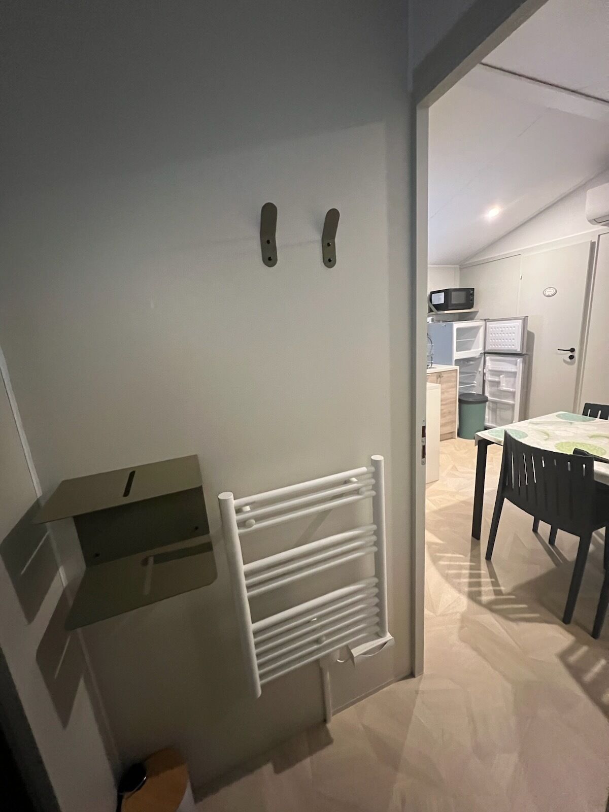 A compact kitchen with a built-in microwave, a refrigerator, and a dining area with a table and chairs.