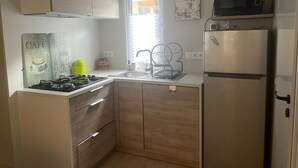 A compact kitchen with a gas stove, a microwave, and a refrigerator. - Mobile home 200 m from the beach in a friendly, wooded 3* campsite. (Saint-Georges-de-Didonne)