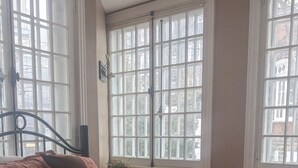 Une chambre avec un grand lit, de nombreuses fenêtres et un plancher en bois.