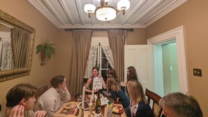 Une salle à manger avec un lustre, un miroir et une plante en pot.