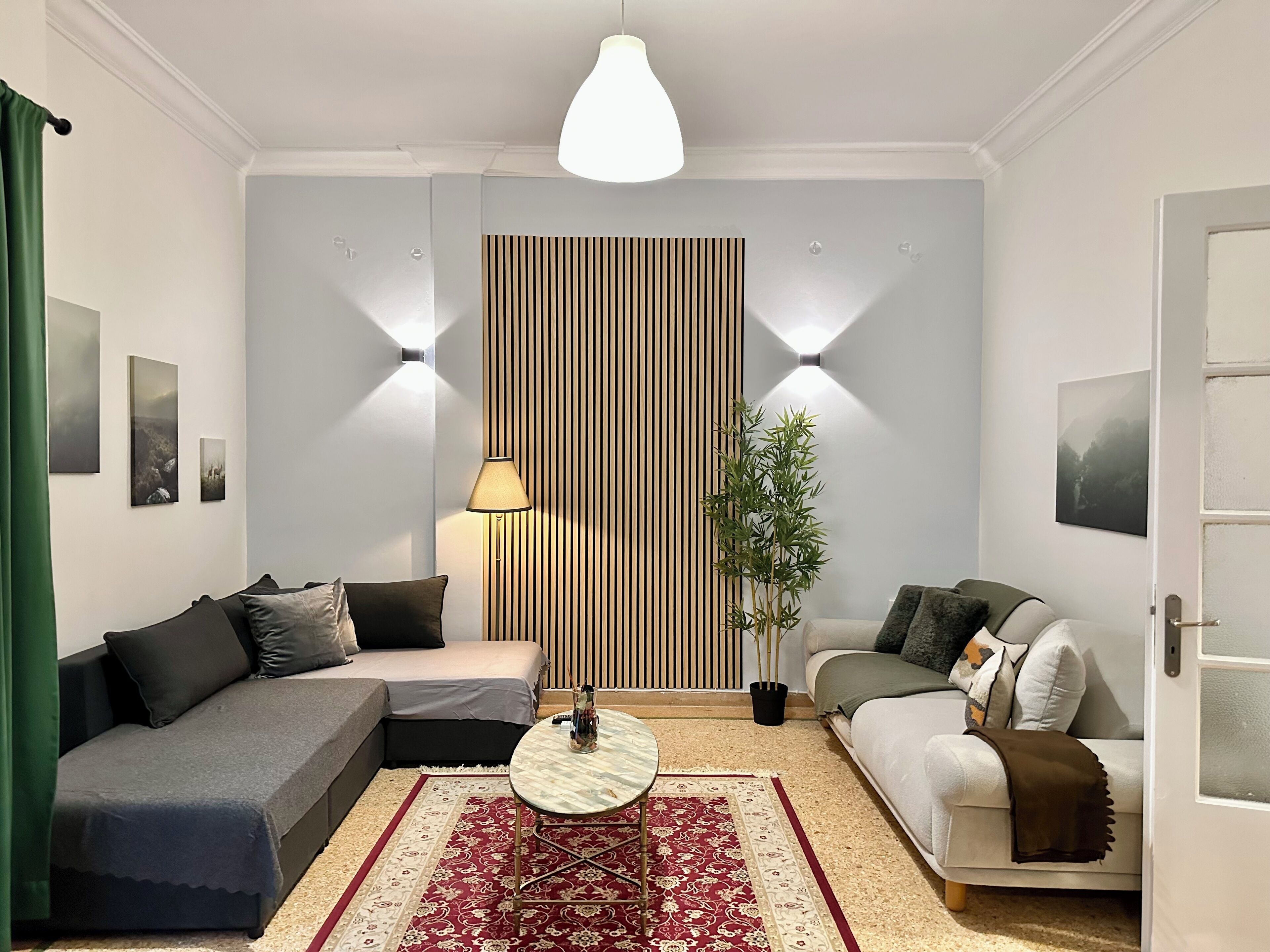 Una sala moderna con un sofá, un sillón más pequeño, una mesa de centro redonda y una planta decorativa.