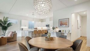 Una cocina moderna con armarios blancos, una isla central y un comedor con una mesa redonda y sillas.