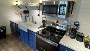 A modern kitchen with stainless steel appliances, blue cabinets, and a marble countertop.