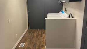 A compact kitchen with a built-in dishwasher, a small countertop, and a dark gray cabinet above the sink.