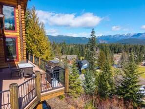 A log cabin with a deck, outdoor grill, and a scenic mountain view.