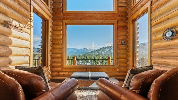 A log cabin interior with a view of mountains and a balcony. - Miracle Lodge - Hot Tub, Golf & Mountain Views (Leavenworth)