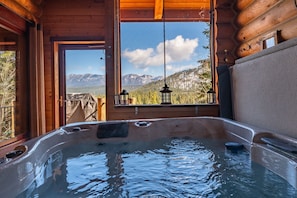 A hot tub with a view of mountains through a window.