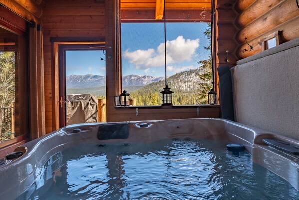 A hot tub with a view of mountains through a window.