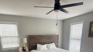 Ein Schlafzimmer mit einem hölzernen Bett, einem Nachttisch mit Lampe und einem Deckenventilator.