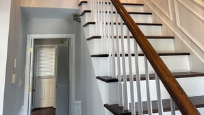 Eine Treppe mit weißen Geländern und dunklen Holzhäusern, die zu einer oberen Etage führt.