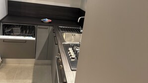 A modern kitchen with grey cabinets, a black countertop, and a stainless steel stove.