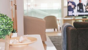 Un salon moderne avec un canapé, un téléviseur et une petite table ornée de coquillages décoratifs.